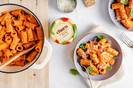Rigatoni pasta in vibrant red sauce, topped with cheese and basil, served with Churn Bruschetta Butter.